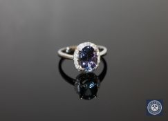 A 14ct white gold tanzanite and diamond halo ring, the central, oval-cut,