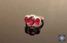 A 14ct white gold ruby and diamond ring, three oval-cut deep red rubies weighing a total of 5.