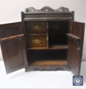 A Victorian oak double door smoker's cabinet with carved panel doors