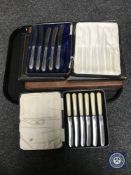 A tray containing a set of five cased silver handled butter knives,