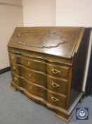 An early 20th century oak serpentine fronted bureau