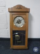 A 20th century continental oak cased eight day wall clock with pendulum and key
