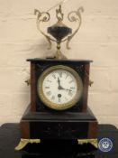 A Victorian marble and slate mantel clock on brass feet surmounted by an urn,