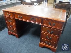 A reproduction twin pedestal desk fitted nine drawers with a tooled leather inset panel