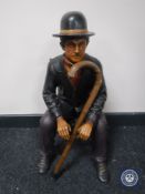 A painted wooden figure - Charlie Chaplin on chair