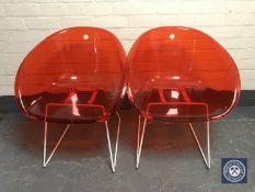 A pair of red perspex bucket seats on metal legs