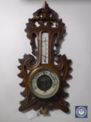 A carved oak cased aneroid barometer