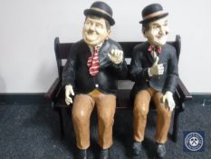 Two painted figures of Laurel & Hardy on bench