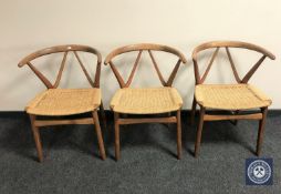 A set of three teak rush seated elbow chairs