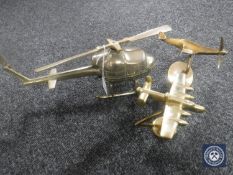 A brass helicopter together with two brass military aircraft on stands