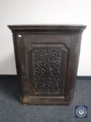 A 19th century oak hanging corner cupboard with carved panel door