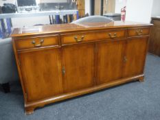 An inlaid yew wood four door sideboard fitted three drawers
