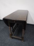 An antique oak gateleg table fitted a drawer on turned legs
