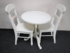 A circular painted pedestal kitchen table and two chairs