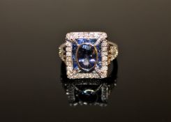 An 18ct white gold tanzanite, sapphire and diamond ring, the central oval-cut tanzanite weighing 0.