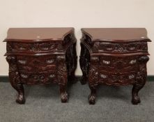 A pair of heavily carved three drawer bedside chests, width 68 cm.