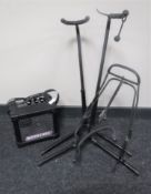 A Roland Microcube amplifier together with three guitar stands