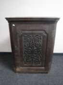 An early 19th century oak hanging corner cabinet with carved panel door