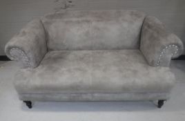 A contemporary two seater settee upholstered in a grey fabric