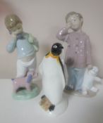 Two Nao figures of boys with teddy bears together with a Poole figure of a penguin
