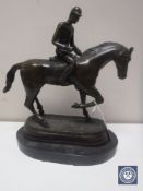 A bronze figure of a horse and jockey on marble base