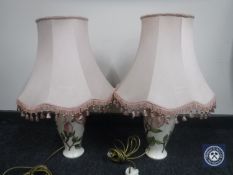 A pair of Moorcroft Pottery cream lamp bases decorated with pink flowers and pink tasseled shades