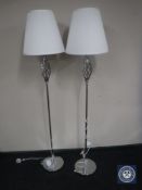 A pair of contemporary chrome floor lamps with white shades