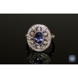 An 18ct white gold tanzanite and diamond cluster ring, a central oval-cut tanzanite weighing 0.