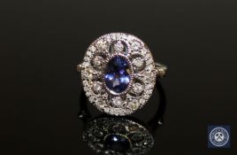 An 18ct white gold tanzanite and diamond cluster ring, a central oval-cut tanzanite weighing 0.