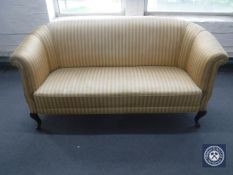 An early 20th century settee upholstered in a gold striped fabric