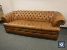 A tan leather Chesterfield style three seater settee,