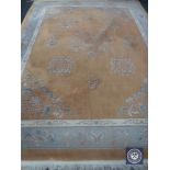 A fringed Chinese style carpet with floral design on peach ground