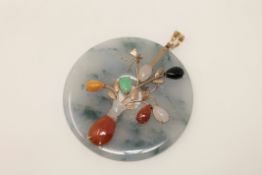 A large jade disc pendant set with various coloured jade mounted in gold