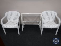 A pair of plastic patio armchairs and a painted bamboo towel rail