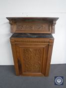An antique carved oak wall cabinet and a similar wall shelf