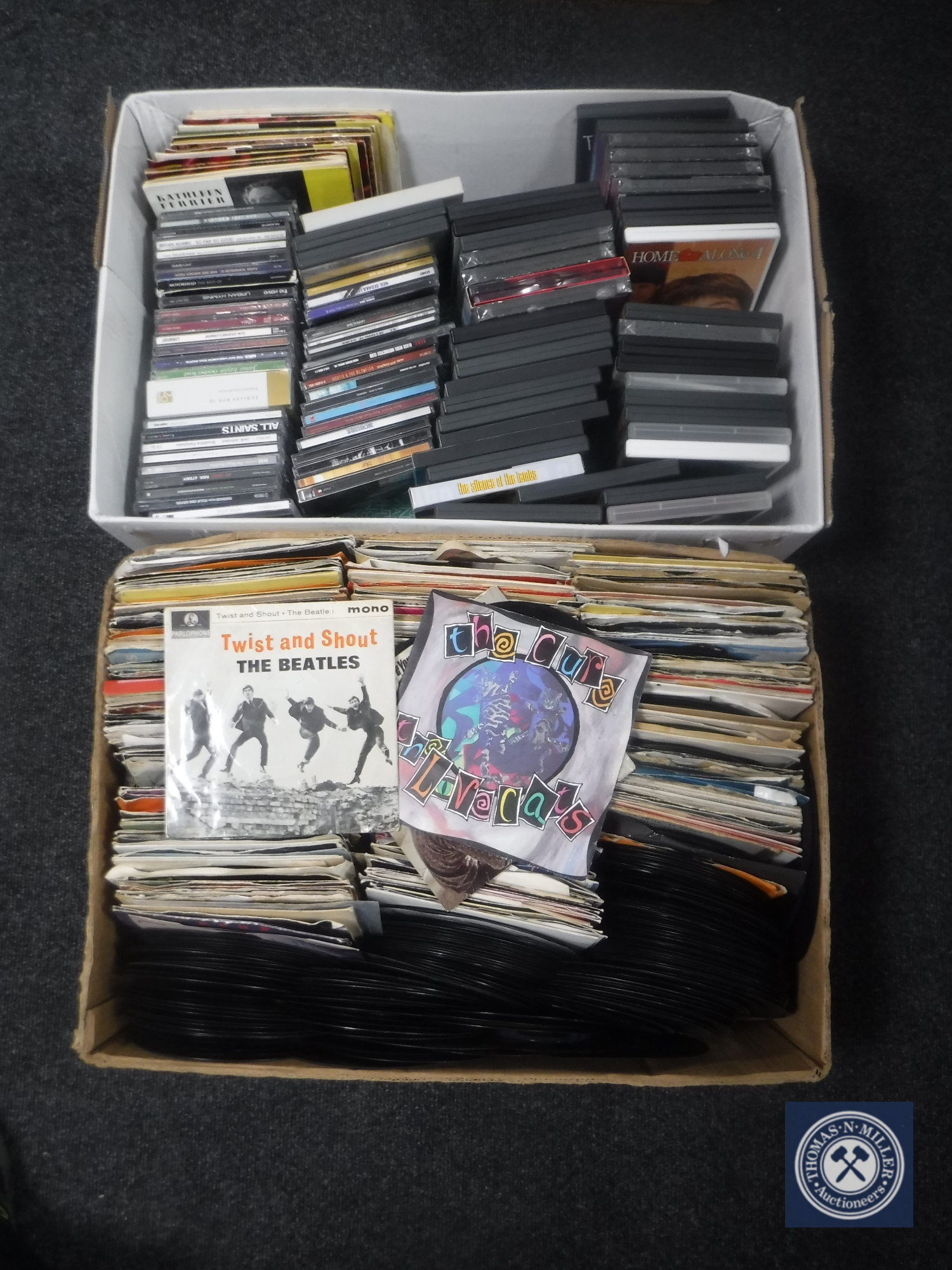 A box of 7" singles - The Beatles, The Jam, The Cure,