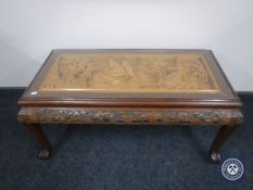 A glass topped carved coffee table