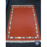 A set of three fringed woolen rugs on red ground