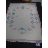 A fringed woolen carpet on pink ground