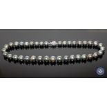 A 14ct white gold pearl and diamond necklace, thirty-seven black/peacock-green Tahitian pearls,