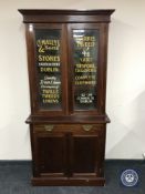 A Victorian mahogany glazed door bookcase with sign writer's advertisement
