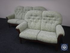 A wooden framed three seater and two seater settee in green floral fabric