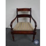 An antique stained pine scroll arm chair