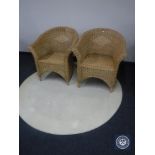 A circular cream rug and two wicker armchairs