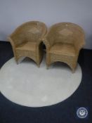 A circular cream rug and two wicker armchairs