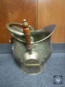 An antique brass coal helmet with shovel and tongs