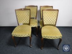A set of four dining chairs upholstered in a gold fleur de lys fabric