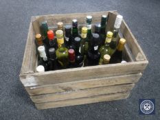 A box containing twenty-four bottles of assorted alcohol and wines and a vintage wooden crate