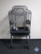 A large metal bird cage with accessories on trolley
