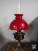 A brass Aladdin oil lamp with chimney and red glass shade